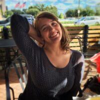 portrait-smiling-young-woman-sitting-sidewalk-cafe